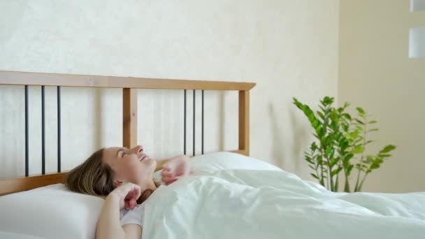 Woman waking up in her bed fully rested. Woman stretching in bed after wake up. - Materiał filmowy, wideo