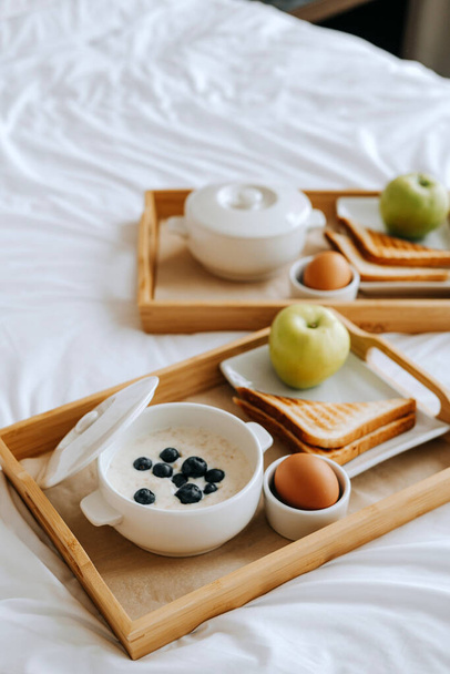 Breakfast in the hotel. Porridge, boiled egg, toast, coffee, porridge with berries on a tray - Foto, immagini
