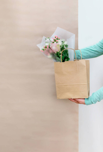 配達サービスの労働者の手白とクラフトの背景に顧客のための紙袋に花を梱包. - 写真・画像