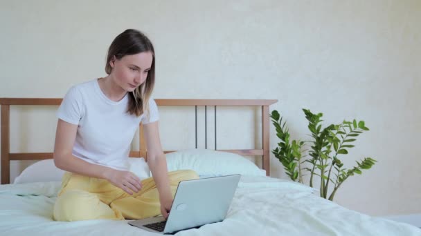 Woman using laptop, sitting in bed, celebrating success, online lottery win, reading good message, chatting in social network in bedroom at home - Кадри, відео