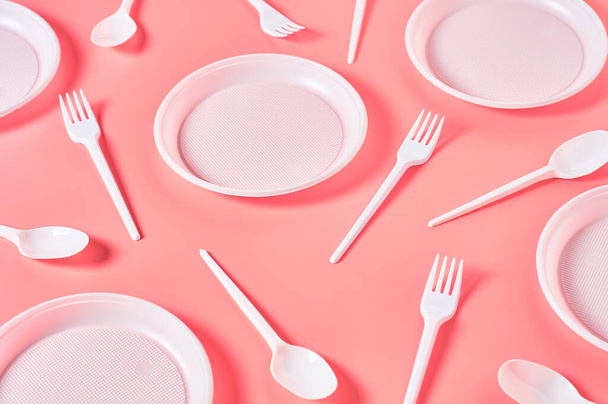 Disposable plastic utensils scattered on pink background. Concept of save environment, ecology, recreation on picnic, party and other events - Foto, Bild