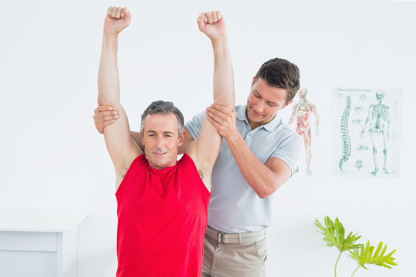 Physiotherapist examining a smiling mature mans arm - 写真・画像