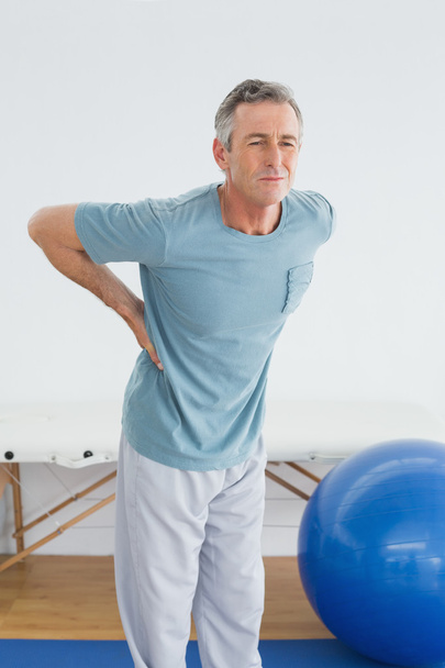 Man with lower back pain in the hospital gym - Φωτογραφία, εικόνα