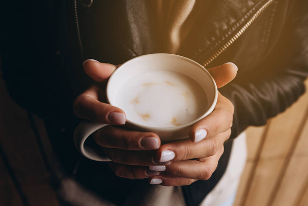 a cup of fragrant morning coffee before work or school. Photo of the female hands  holding a cup with pictures of little hearts. Ideal for advertising or banner - Foto, Bild