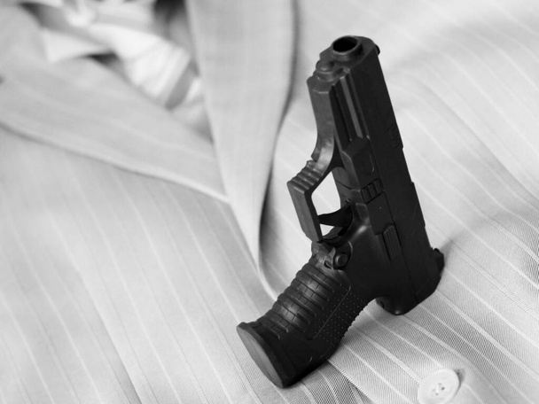 Черный пистолет на мужском пиджаке и галстуке так близко
 - Фото, изображение