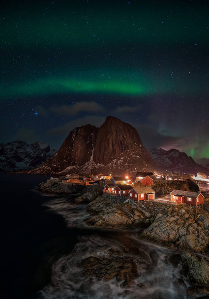 Aurora borealis über beleuchtetem Fischerdorf mit rorbu-Häusern in Norwegen - Foto, Bild