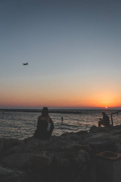 People seeing off the sunset over the Mediterranean Sea on the seacoast in Tel Aviv on a warm evening - Photo, Image