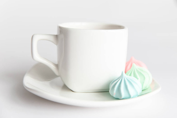 Buenos días. merengues y una taza de café en un platillo sobre un fondo blanco aislado. Cultura del café - Foto, Imagen