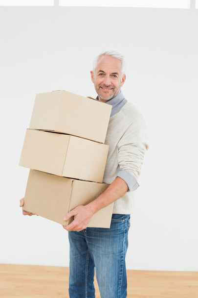 Smiling mature man carrying boxes in a new house - Foto, Imagem