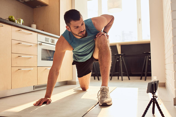 Athletic gentleman having online workout in kitchen - Foto, Imagem