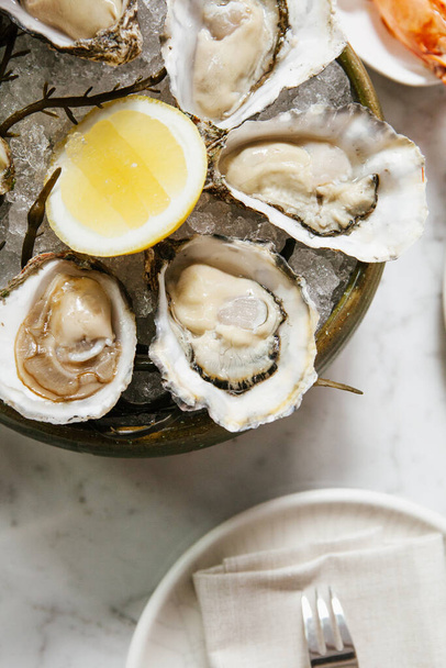 Austern mit Zitronen-Meeresfrüchten, feines Essen aus nächster Nähe. Frische Austern auf Eis. Lebensmittel, teuer. - Foto, Bild