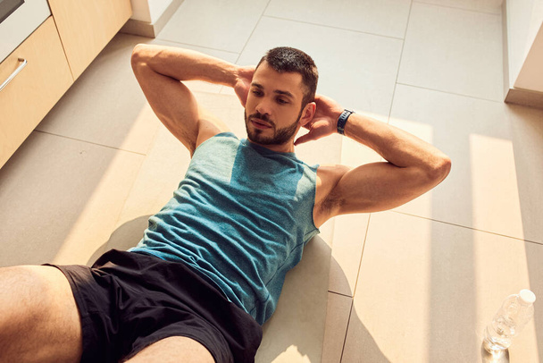 Athletic gentleman doing abdominal exercise at home - Foto, afbeelding