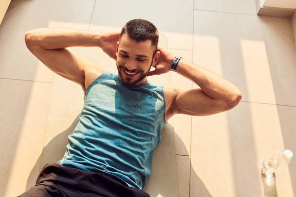 Cheerful young man doing abdominal exercise at home - Foto, Imagen