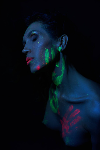 Sexy Nude woman in neon light, UV paint on the woman face and body. Perfect figure and Breasts of a woman, beautiful hair - Фото, изображение