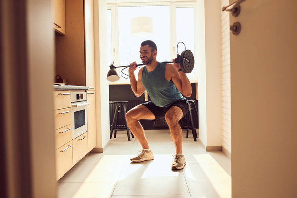 Cheerful gentleman doing exercise with floor lamp - Foto, Imagen