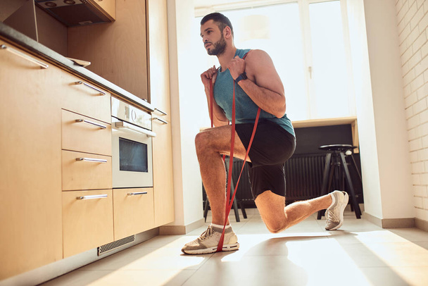 Athletic gentleman doing exercise with elastic fitness band - Fotoğraf, Görsel