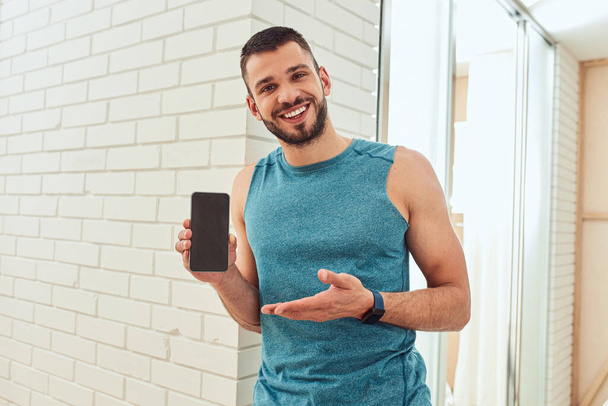 Handsome young man holding cellphone and smiling - Photo, Image