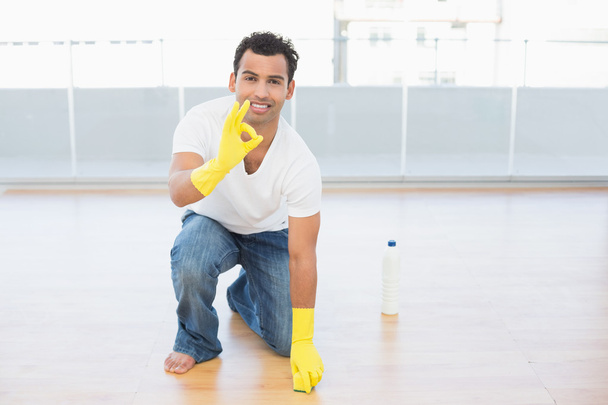 Smiling man cleaning the floor while gesturing okay sign - Photo, image