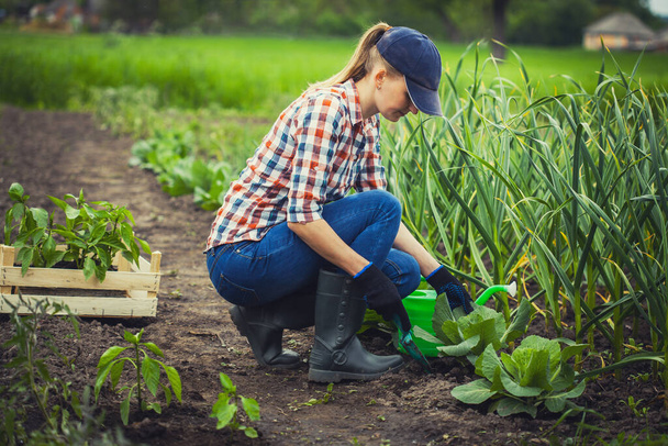 woman farmer works in a garden in a plaid shirt. - Zdjęcie, obraz