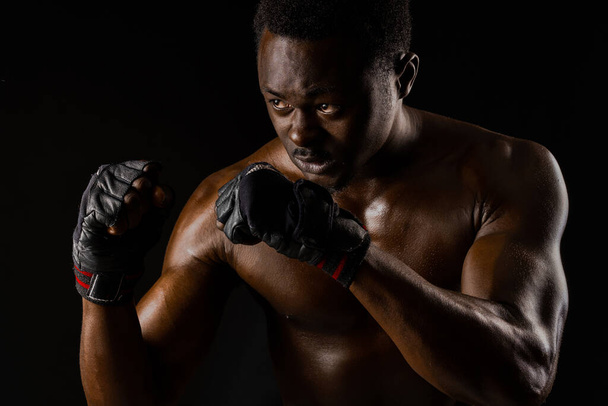 Luchador africano atlético sobre fondo negro. El hombre desvestido de piel oscura muestra una pelea. Anuncio de club deportivo y gimnasio. Boxeo profesional y karate
 - Foto, Imagen