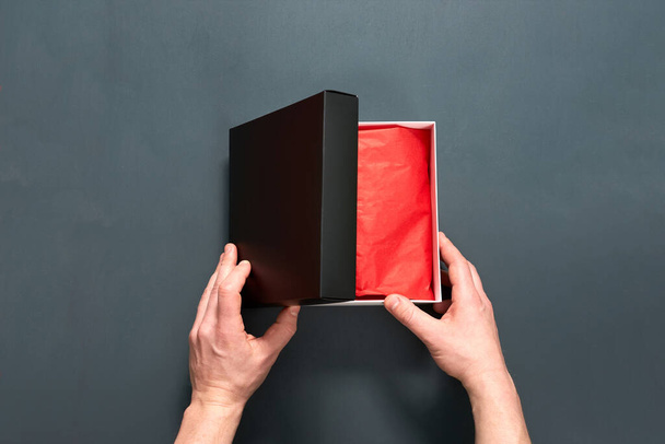 Man holding gift box with present on grey wooden table. Closeup view. - Photo, Image