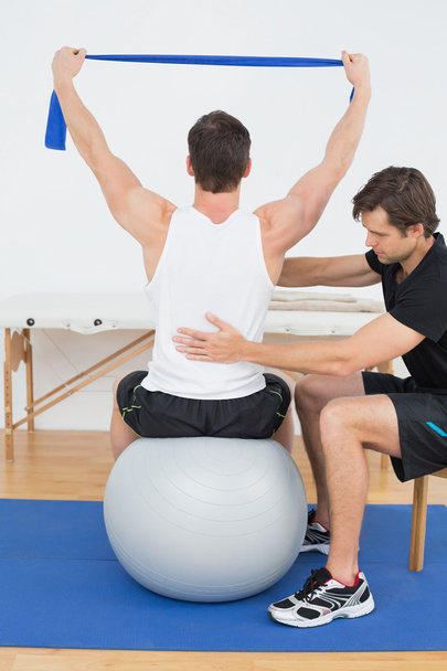 Man on yoga ball working with a physical therapist - Foto, Imagen