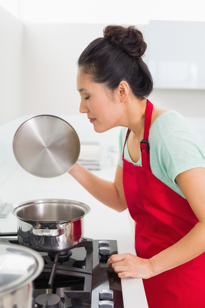 Side view of a young woman preparing food in kitchen - Foto, imagen