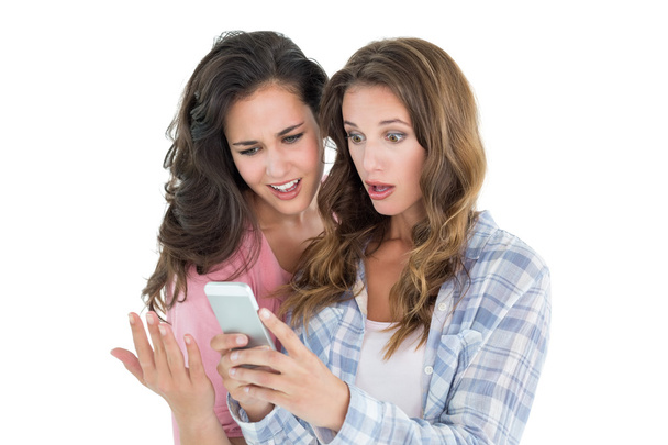 Shocked female friends looking at mobile phone - Foto, imagen