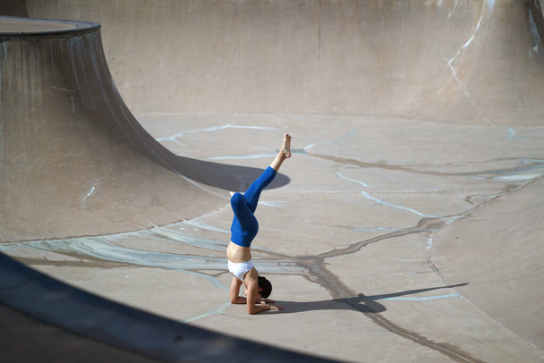 Ακολουθώντας την τάση της γιόγκα σε δημόσιους χώρους, Ασιάτισσα Κινέζα κάνει γιόγκα σε δημόσιο πάρκο skate - Φωτογραφία, εικόνα