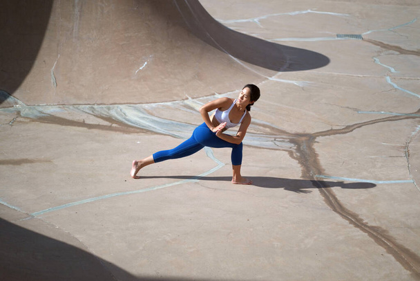 Naar aanleiding van de trend van het doen van yoga in openbare ruimtes, Aziatische Chinese Vrouw doet Yoga in openbaar skate park - Foto, afbeelding