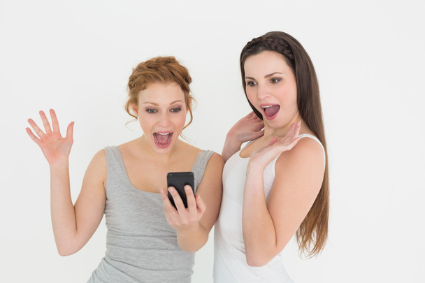 Shocked casual young female friends with mobile phone - Foto, Imagen
