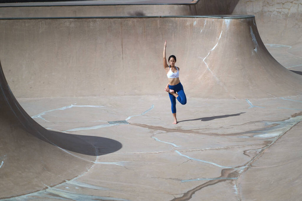 Following the trend of doing yoga in public spaces, Asian Chinese Woman does Yoga in public skate park - Photo, Image