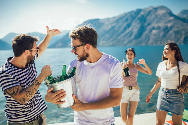 Groupe d'amis traînant avec de la bière à la plage - Photo, image
