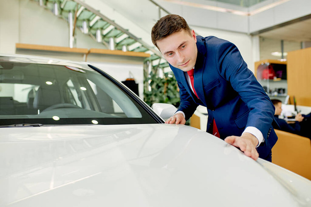 handsome businessman checking, examining new car before making purchase - 写真・画像