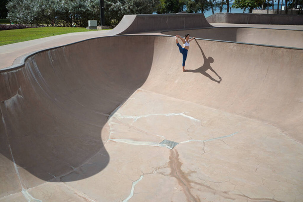 Ακολουθώντας την τάση της γιόγκα σε δημόσιους χώρους, Ασιάτισσα Κινέζα κάνει γιόγκα σε δημόσιο πάρκο skate - Φωτογραφία, εικόνα