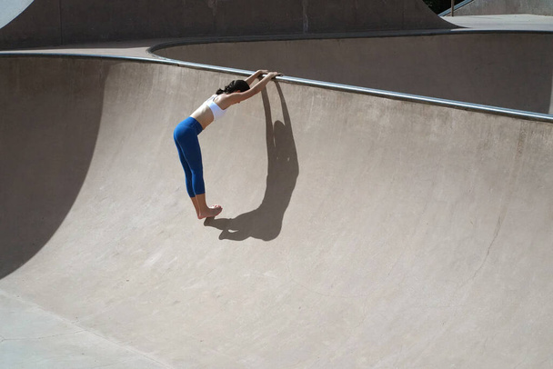 Asian Chinese athlete doing stretching at skatepark using the elements - Foto, Imagem