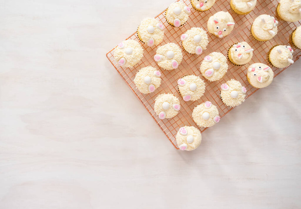Deitado. Decoração de cupcakes de baunilha com uma cobertura de creme de manteiga branco e orelhas de coelho para a Páscoa. - Foto, Imagem