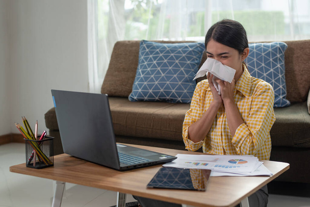 Joven mujer de negocios asiática enferma, ella cierra la nariz y la boca mientras estornuda
 - Foto, imagen