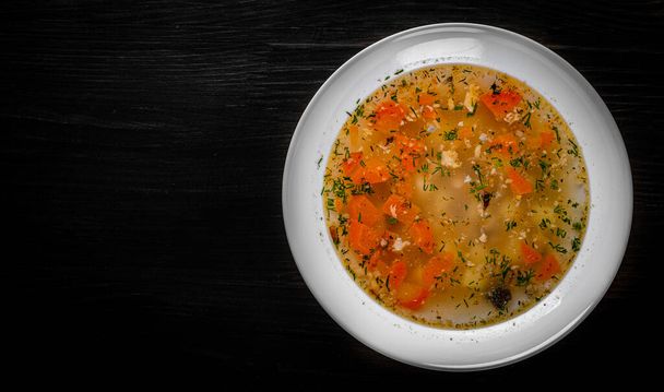 Fresh fish soup in white plate on black wooden table background - Fotó, kép