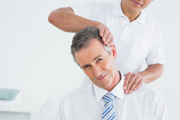Male chiropractor doing neck adjustment - Foto, Bild