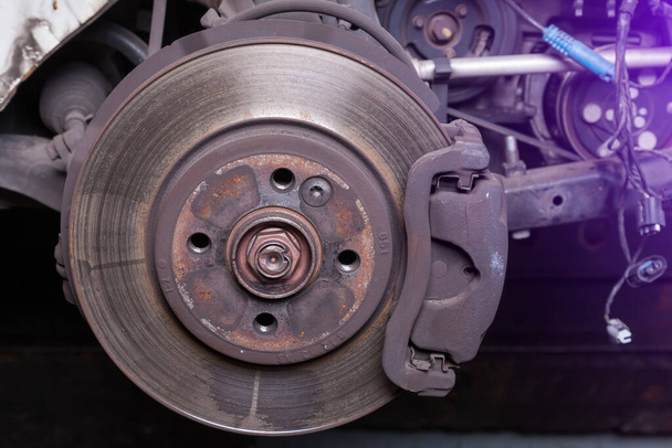 Close-up metal disk in blue backlight - main element of brake system. Friction surface for brake pads. When braking, the pads are pressed against the disk and, due to the friction force, stop rotation - Photo, Image