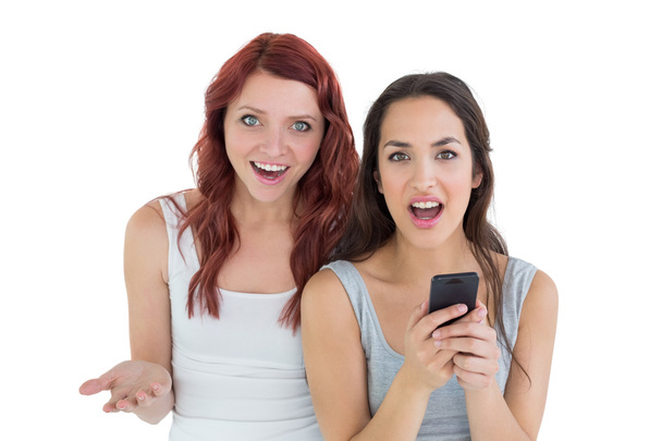 Shocked casual young female friends with mobile phone - Foto, Imagem