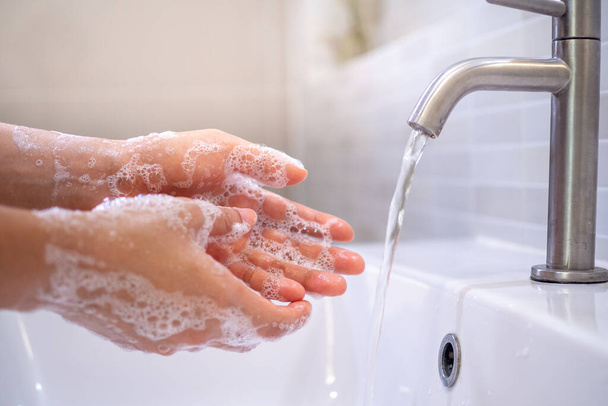 Genç bir kadının elini banyo lavabosunda sabun jeliyle yıkayarak covid19 virüsünün yayılmasını engellemek için yakın plan. Sağlık hizmeti kavramı - Fotoğraf, Görsel