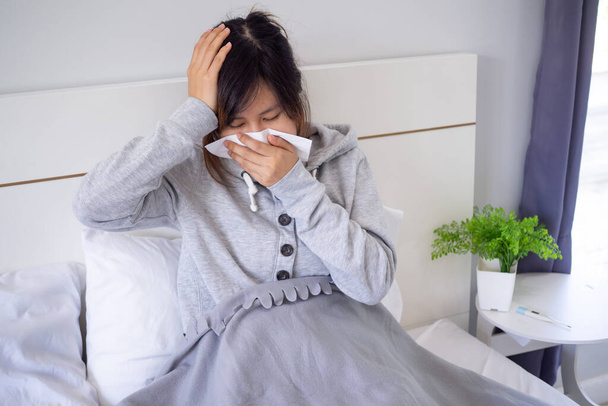 Szédülésben szenvedő ázsiai nők allergiában szenvednek, és zsebkendővel takarják be az orrukat. Mert folyton tüsszent az ágyban a hálószobában.. - Fotó, kép