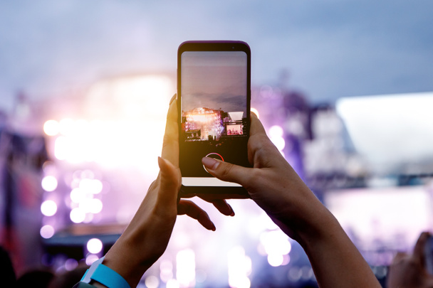Uma menina está tirando fotos de um concerto de rua no telefone - Foto, Imagem