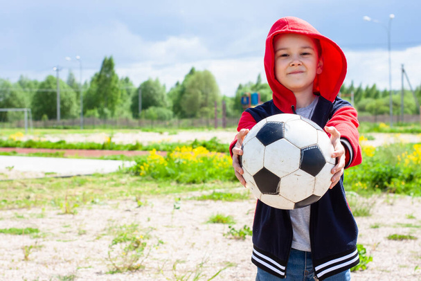 a boy in a red jacket holds out a ball. children ask to play. play with children - Фото, изображение