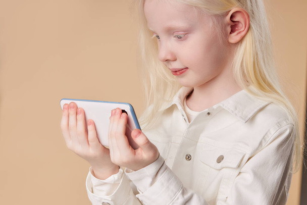 albino child holding white smartphone in hands isolated - Fotoğraf, Görsel