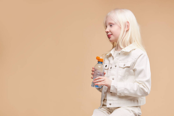 side view on albino child holding water bottle - Фото, изображение