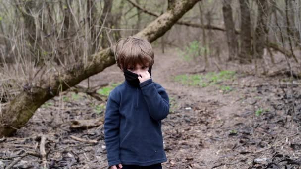 Młody chłopiec w lesie w czarnej masce medycznej wirusa Covid-19 - Materiał filmowy, wideo