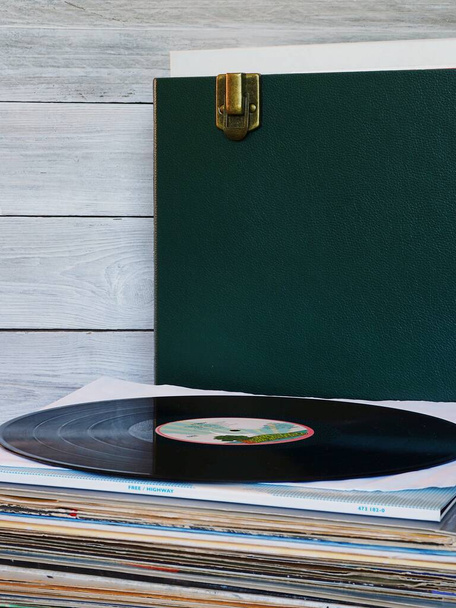 stack of vinyl records with record box and grey weathered wood background - Zdjęcie, obraz